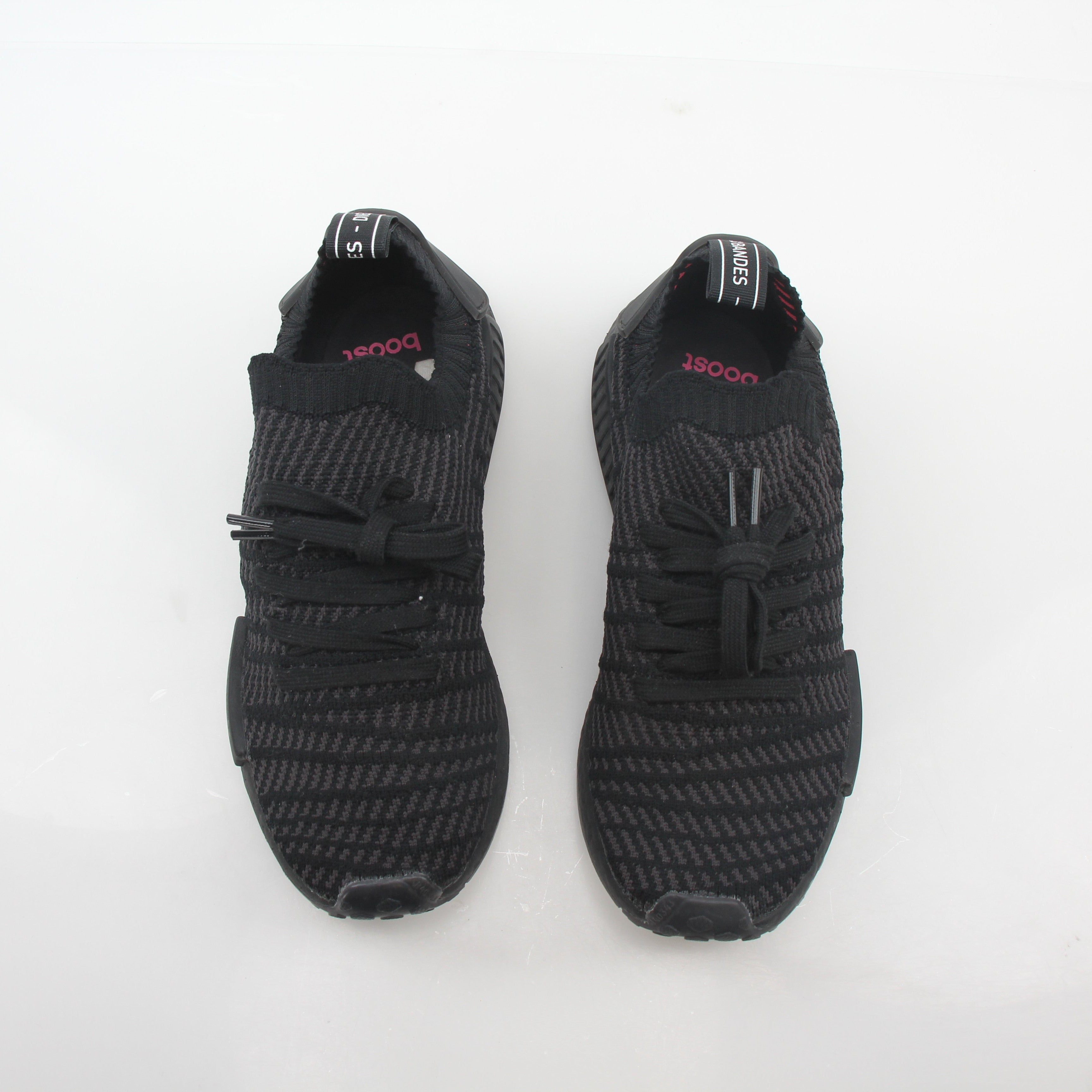 Adidas NMD R1 STLT Triple Black Primeknit sneakers in black with Boost midsole and signature branding on the side.
