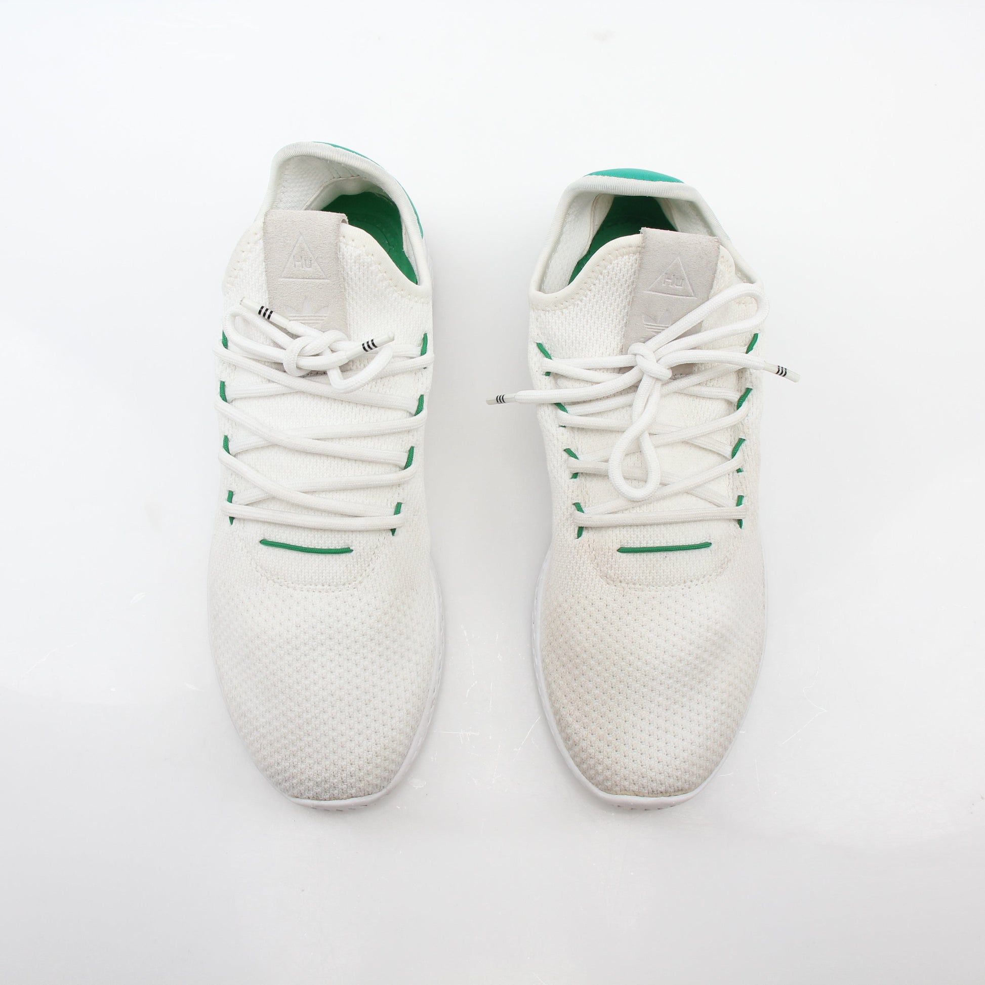 White and green Adidas x Pharrell Williams Tennis Hu sneakers with sporty design and comfortable fit.
