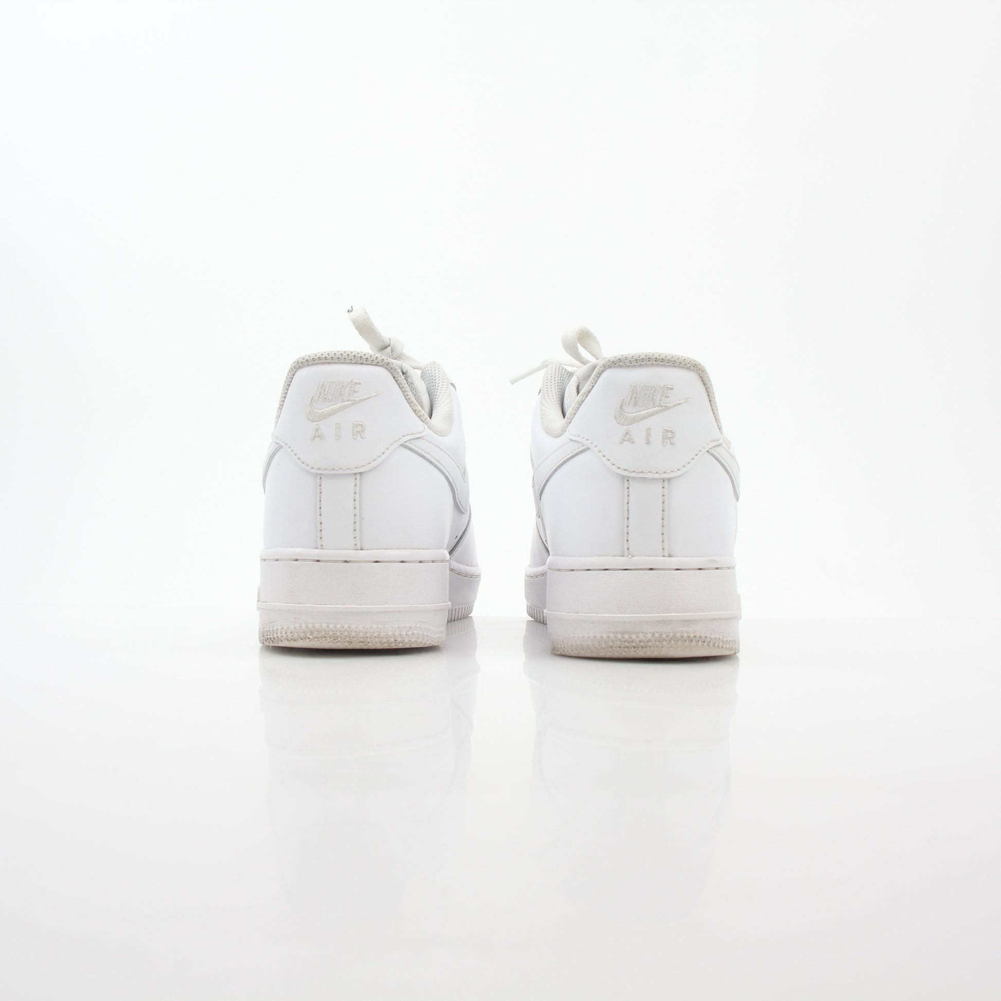 White Nike Air Force 1 ’07 Low sneakers with gold accents, shown from a side angle, featuring classic design and white laces.
