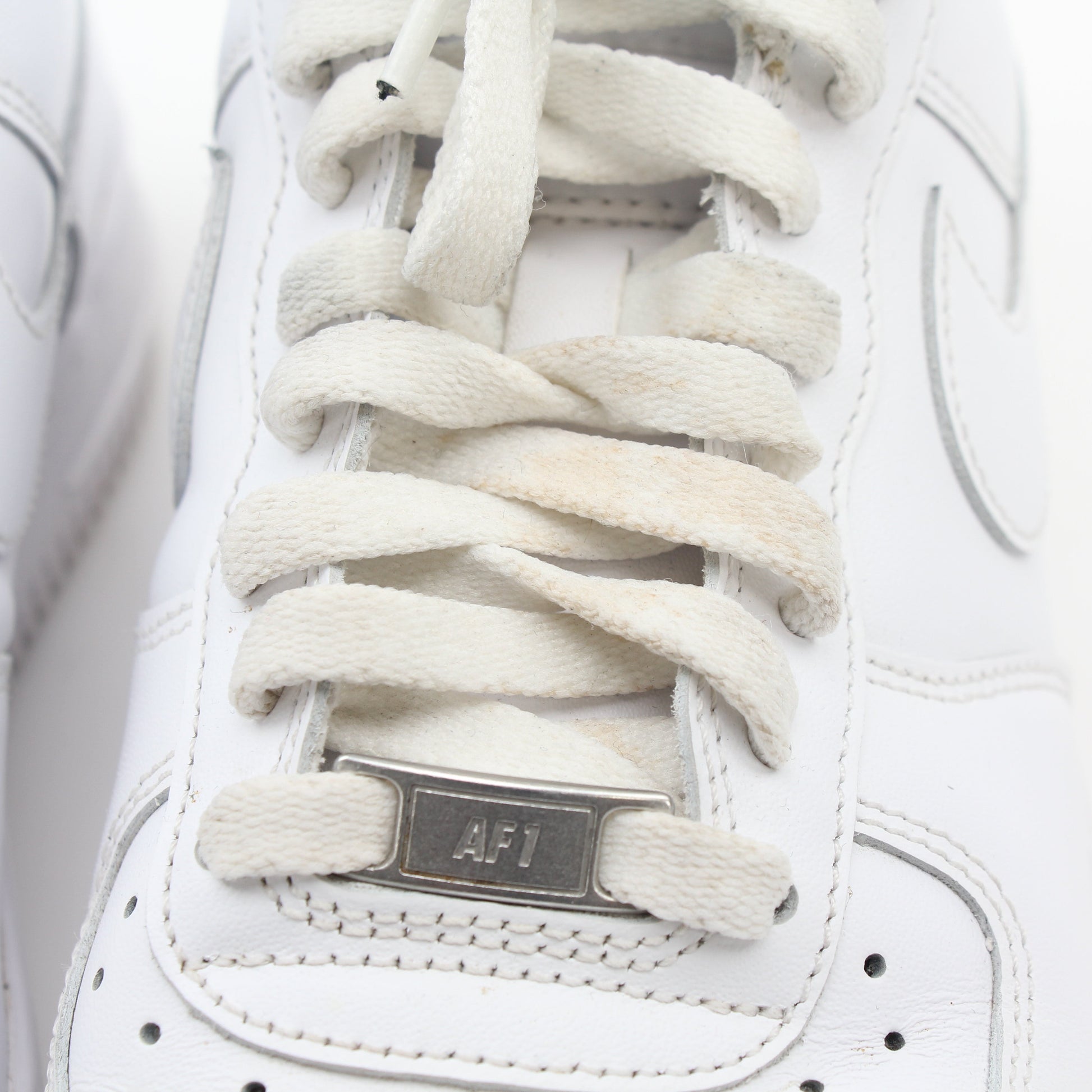 Nike White Air Force 1 ’07 Low sneakers in leather with white laces and rubber soles, displayed on a plain background.