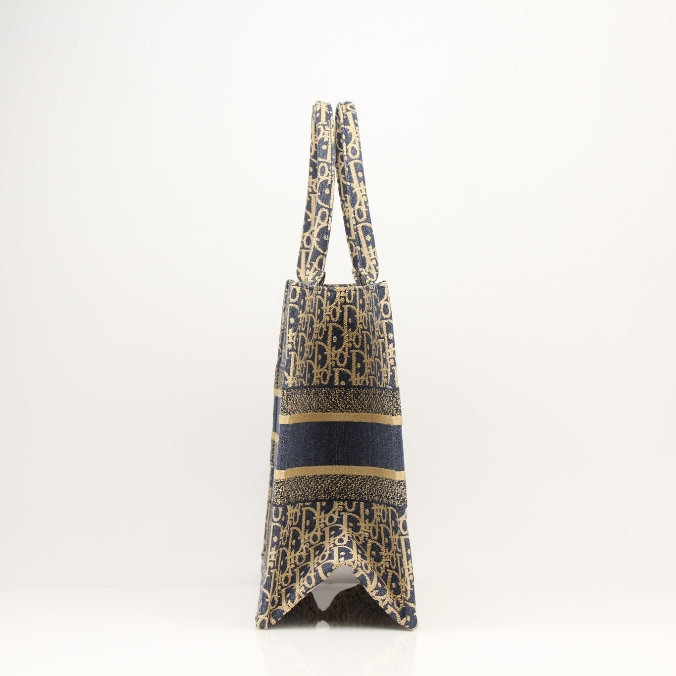 Christian Dior Oblique Book Tote handbag with gold accents, featuring the signature Dior monogram fabric and stylish leather handles.