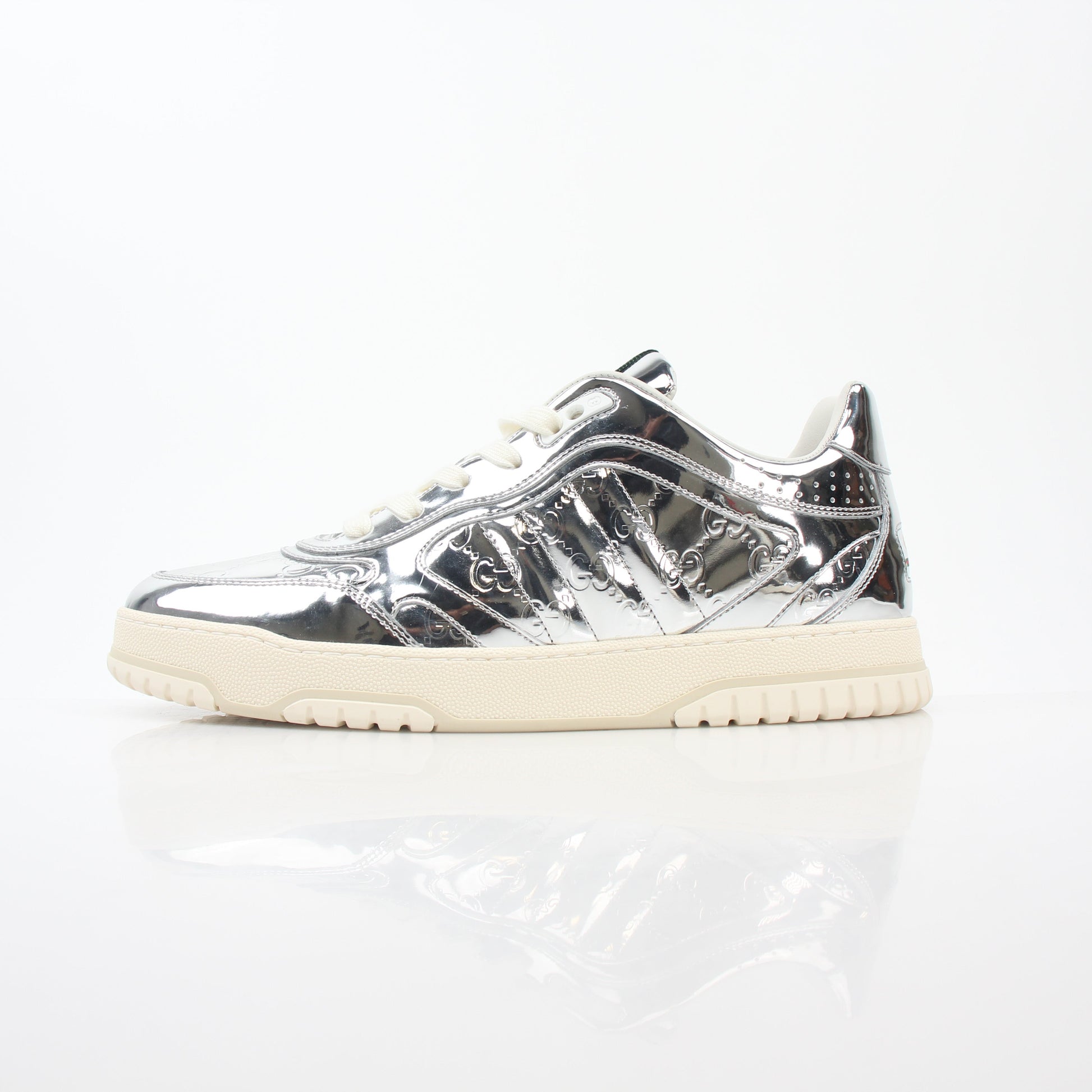 Silver metallic Gucci Re-Web sneakers with white soles and laces, showcasing a stylish and branded shoe design.