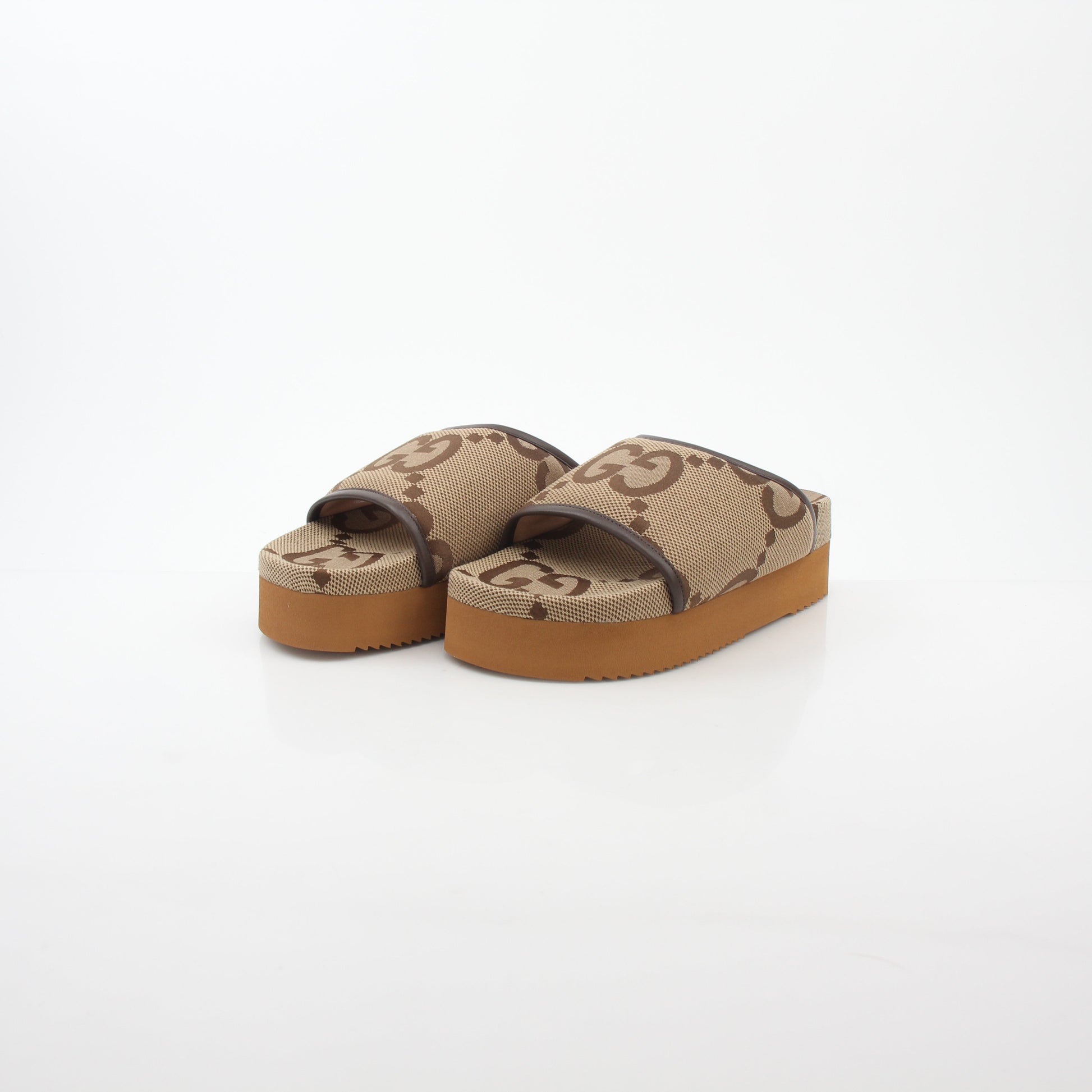 Gucci brown maxi GG platform slide sandals with open toe and thick sole, displayed on a neutral background.