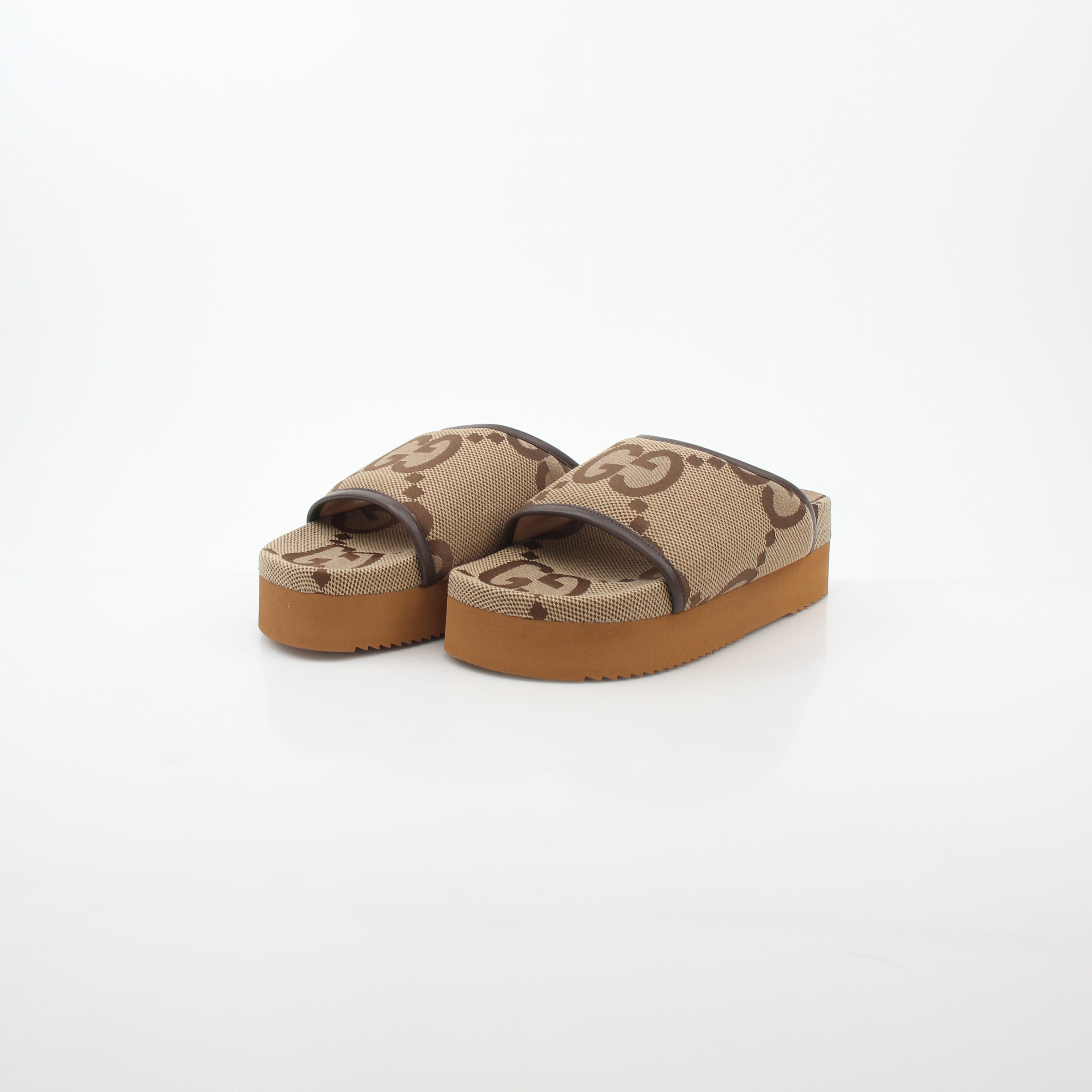 Gucci brown maxi GG platform slide sandals with open toe and thick sole, displayed on a neutral background.