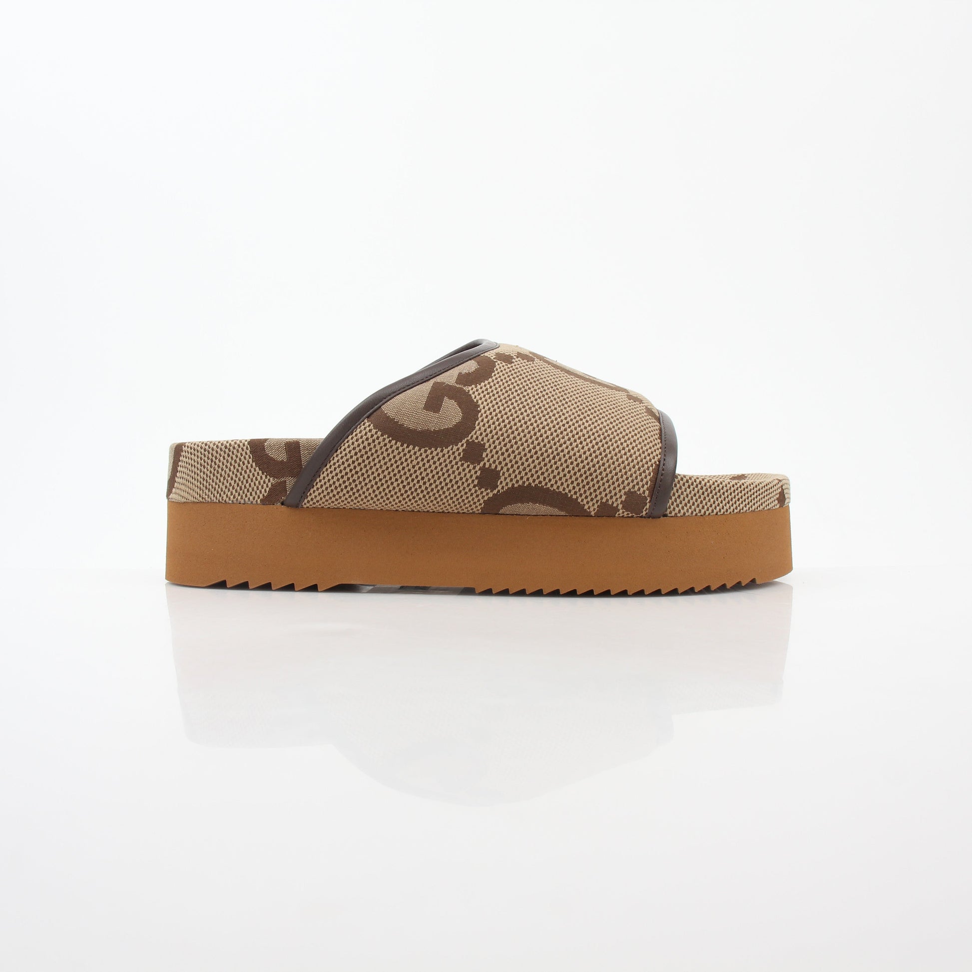 Gucci brown maxi GG platform slide sandals displayed on a foot, showcasing the designer leather shoes with chunky soles.