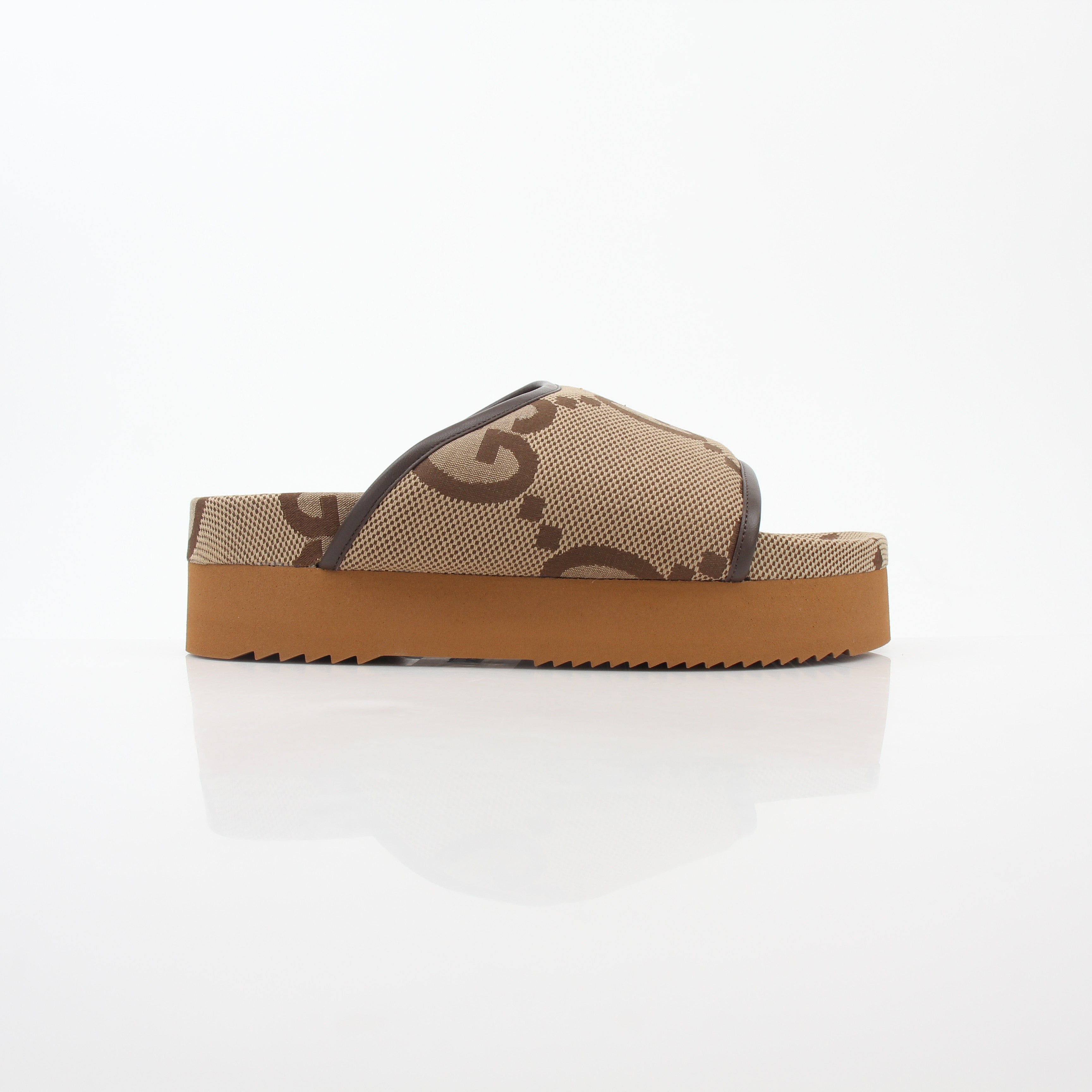 Gucci brown maxi GG platform slide sandals displayed on a foot, showcasing the designer leather shoes with chunky soles.