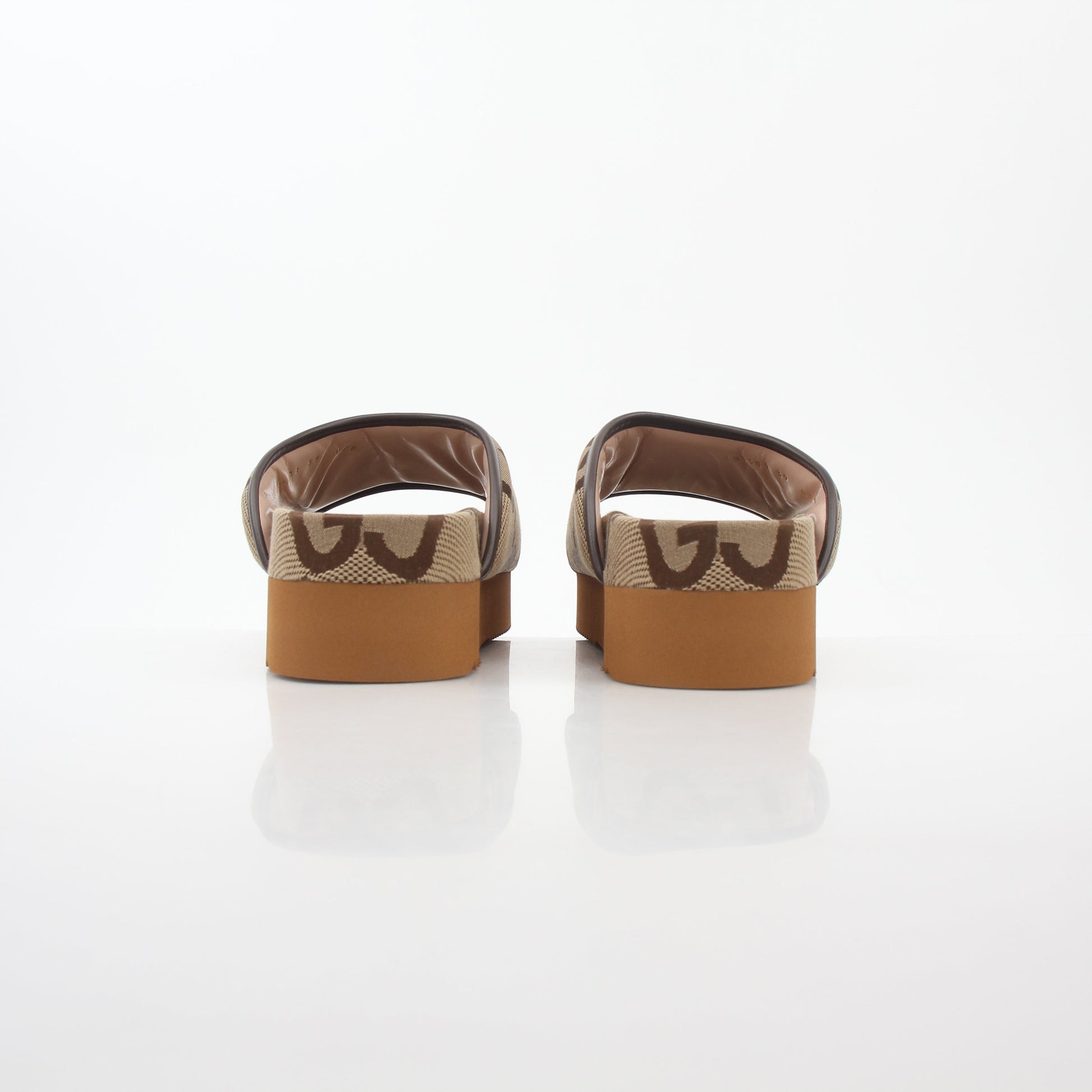 Gucci brown maxi GG platform slide sandals with thick soles and wide straps, displayed on a neutral background.