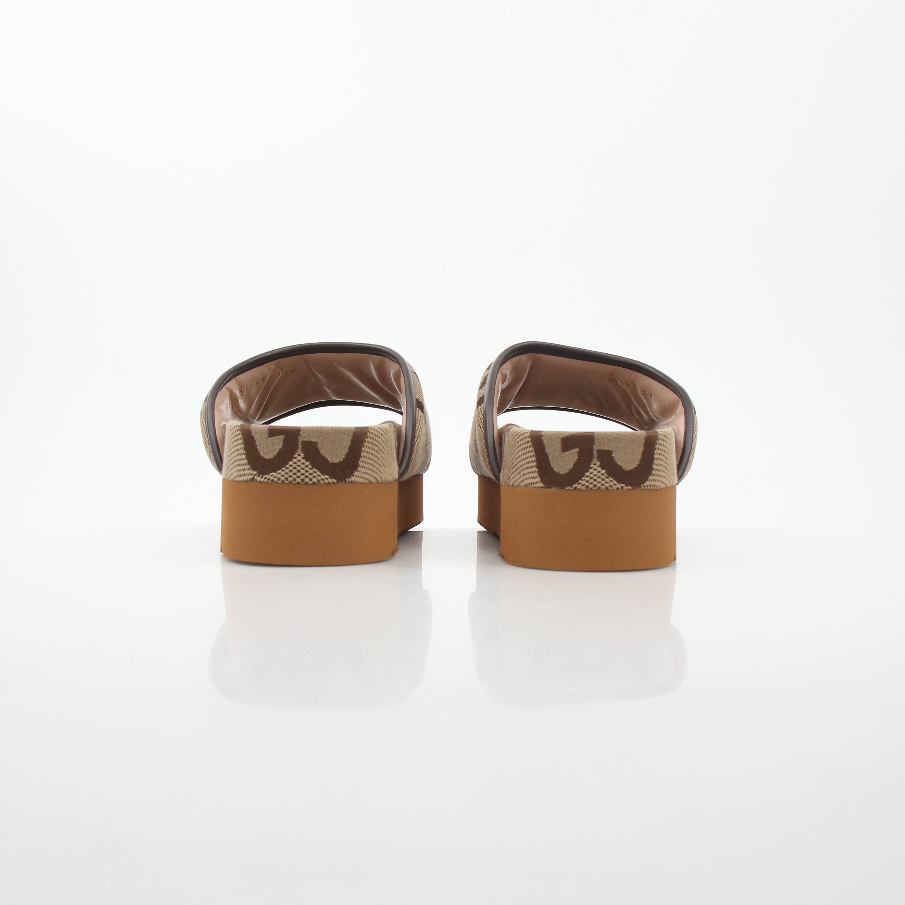 Gucci brown maxi GG platform slide sandals with thick soles and wide straps, displayed on a neutral background.