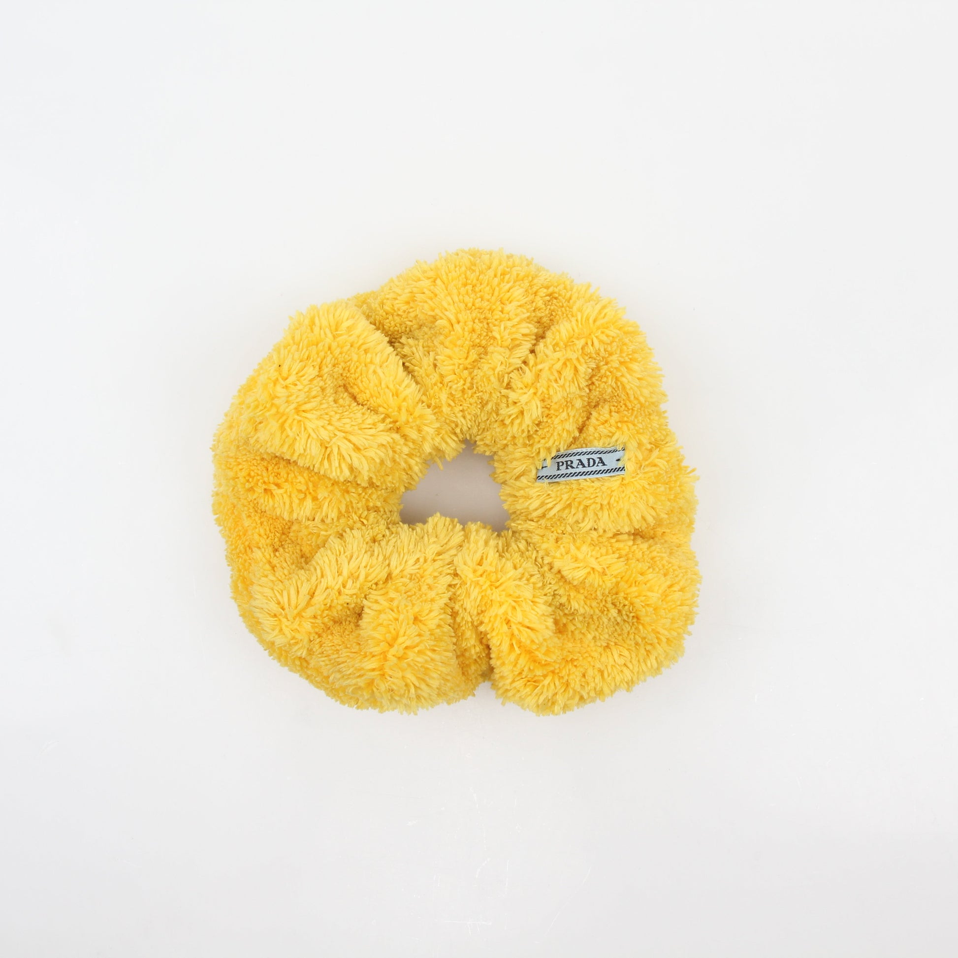 Yellow Prada terry cloth logo scrunchie with gold accents, designed as a stylish accessory for hair or wrist.