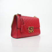 Gucci red GG signature medium shoulder handbag with padlock, featuring gold hardware and a structured leather design.