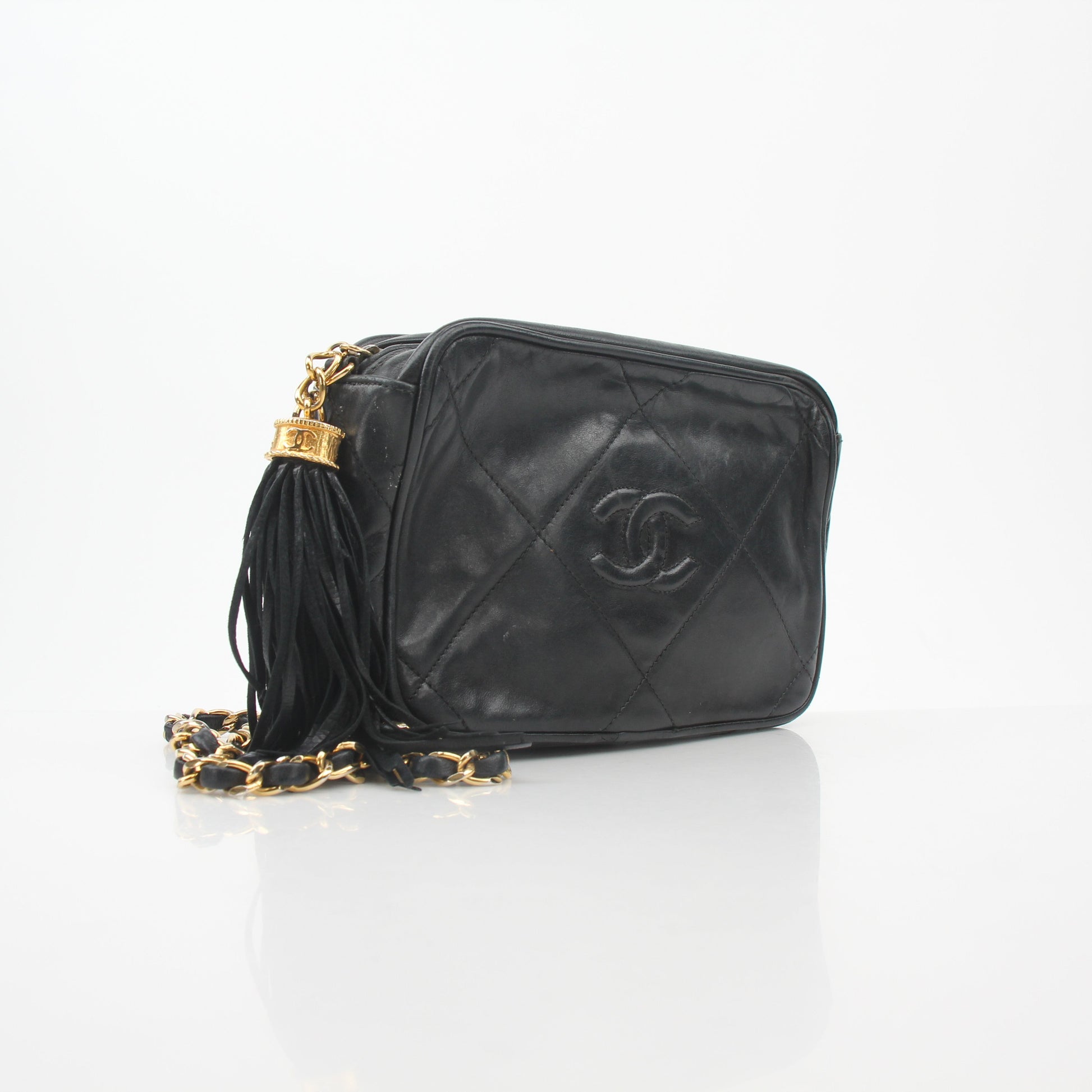 Black vintage Chanel quilted camera handbag with tassel detail and gold hardware, by Gold & Beyond.