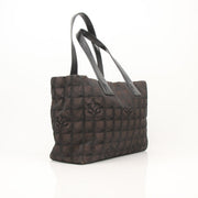 Chanel checked nylon tote handbag with black handles and gold accents, stylish and spacious for everyday use.