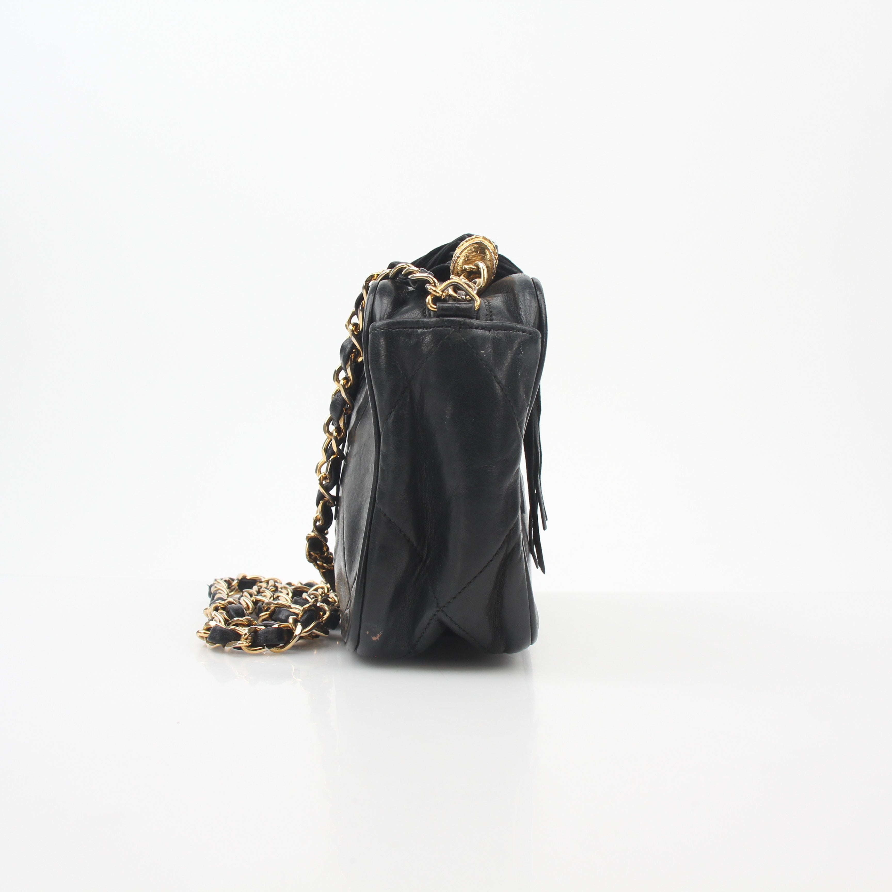 Chanel black vintage quilted tassel camera bag with gold hardware, featuring a hand-stitched leather strap and classic design.