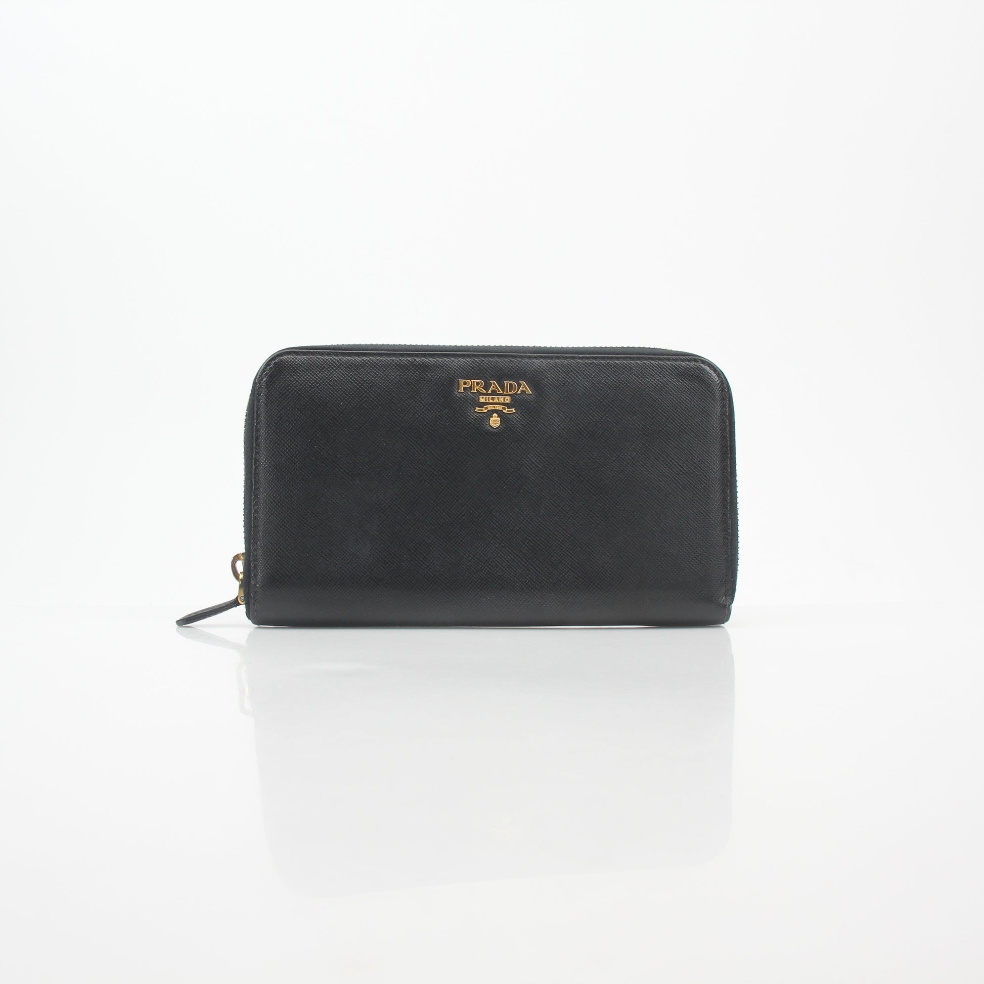 Prada black saffiano leather zip-around wallet with metal logo detail, displayed on a neutral background.