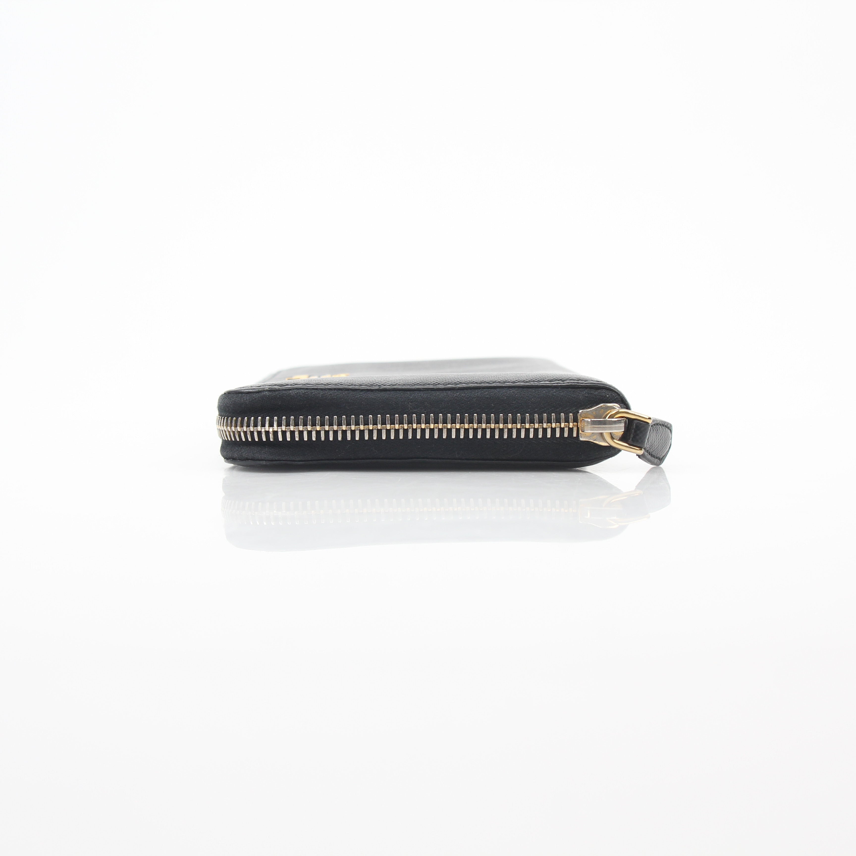 Prada black saffiano leather zip-around wallet with metal logo detail, featuring multiple card slots and a sleek design.