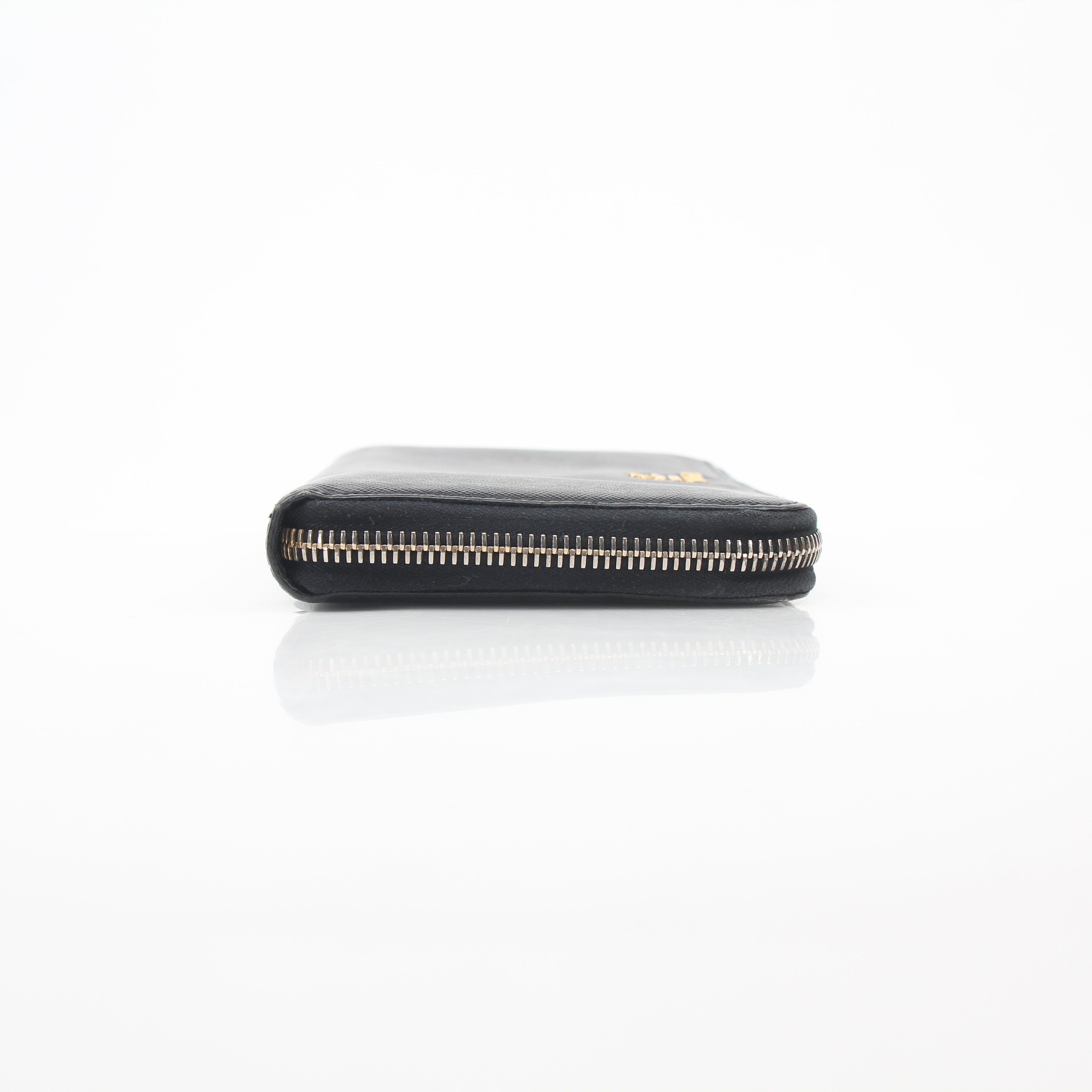 Prada black saffiano leather zip-around wallet with metal logo, featuring a sleek design and multiple card slots.