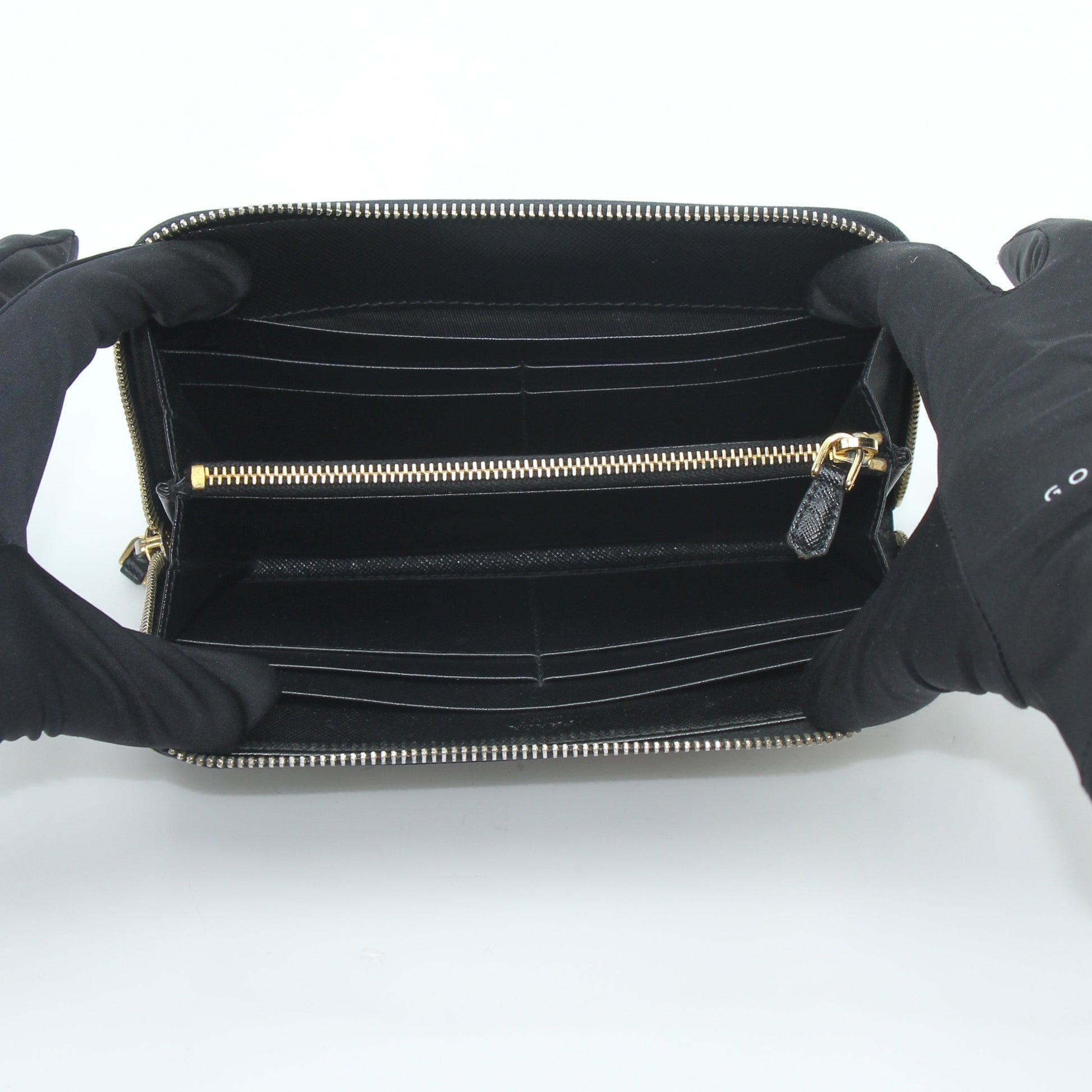 Prada black saffiano leather zip-around wallet with metal logo, featuring sleek design and multiple card slots.
