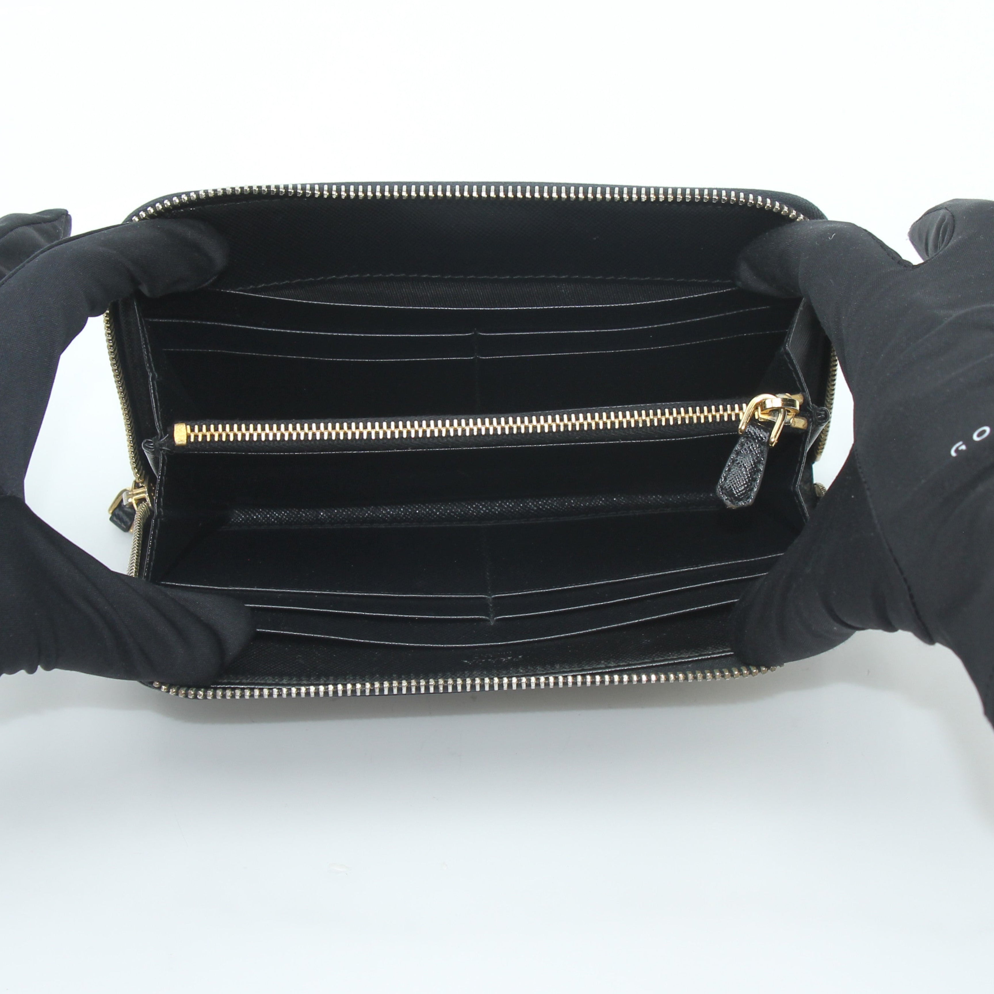 Prada black saffiano leather zip-around wallet with metal logo, featuring sleek design and multiple card slots.