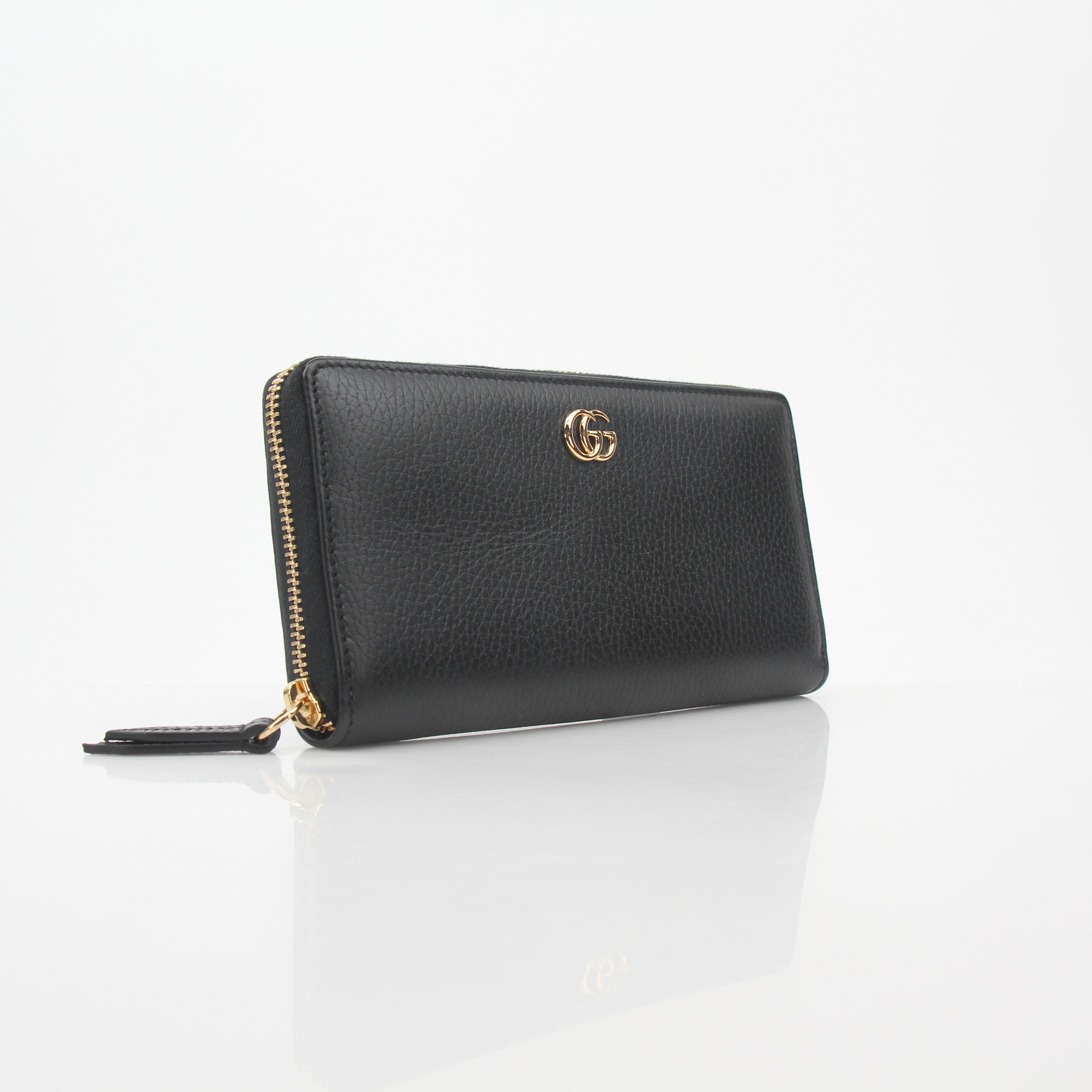 Gucci black GG Marmont zip-around wallet with gold hardware and quilted chevron pattern, featuring a zip closure and brand logo.
