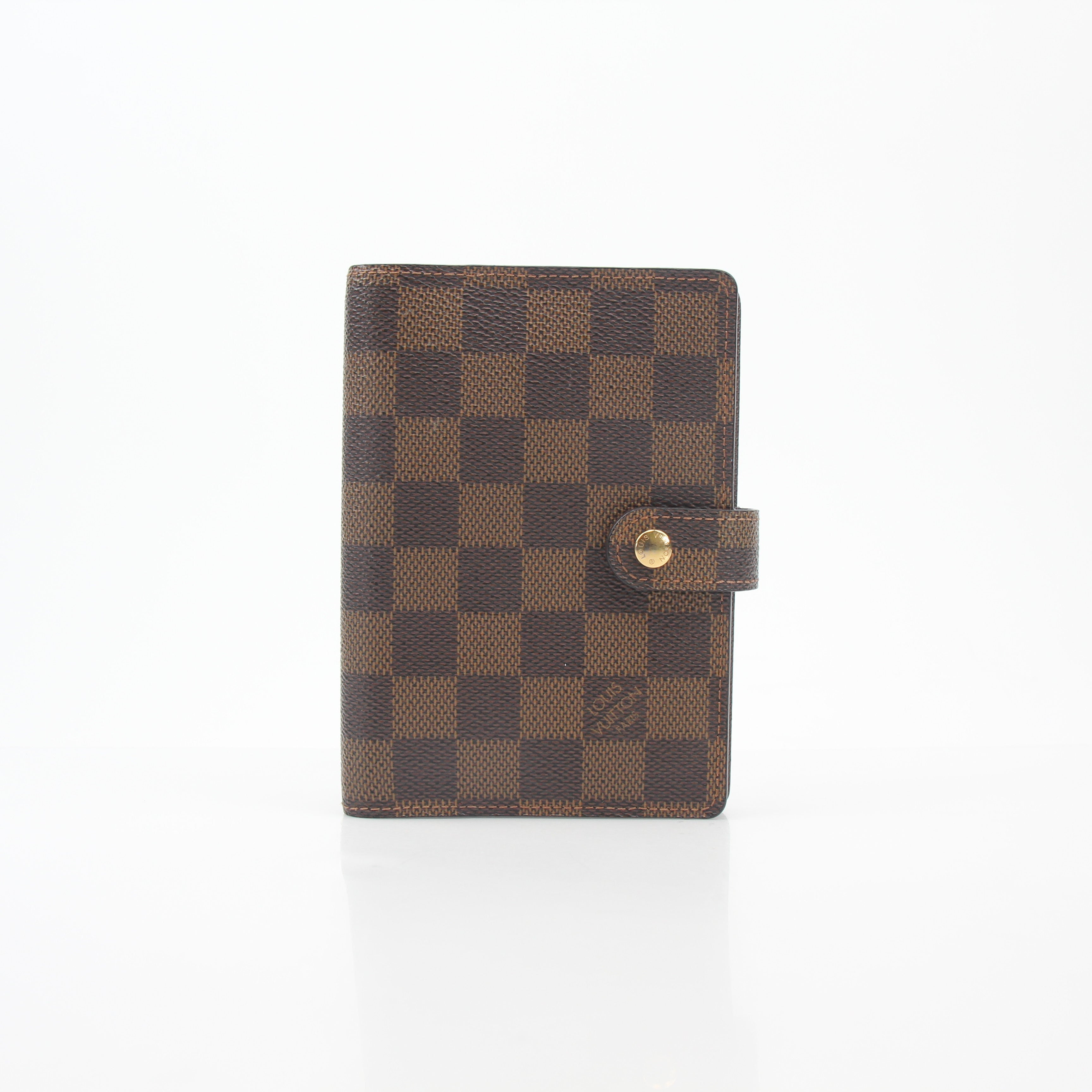 Louis Vuitton Damier Ebene Ring Agenda PM cover in brown checkered pattern with gold accents, designed for accessories and organization.
