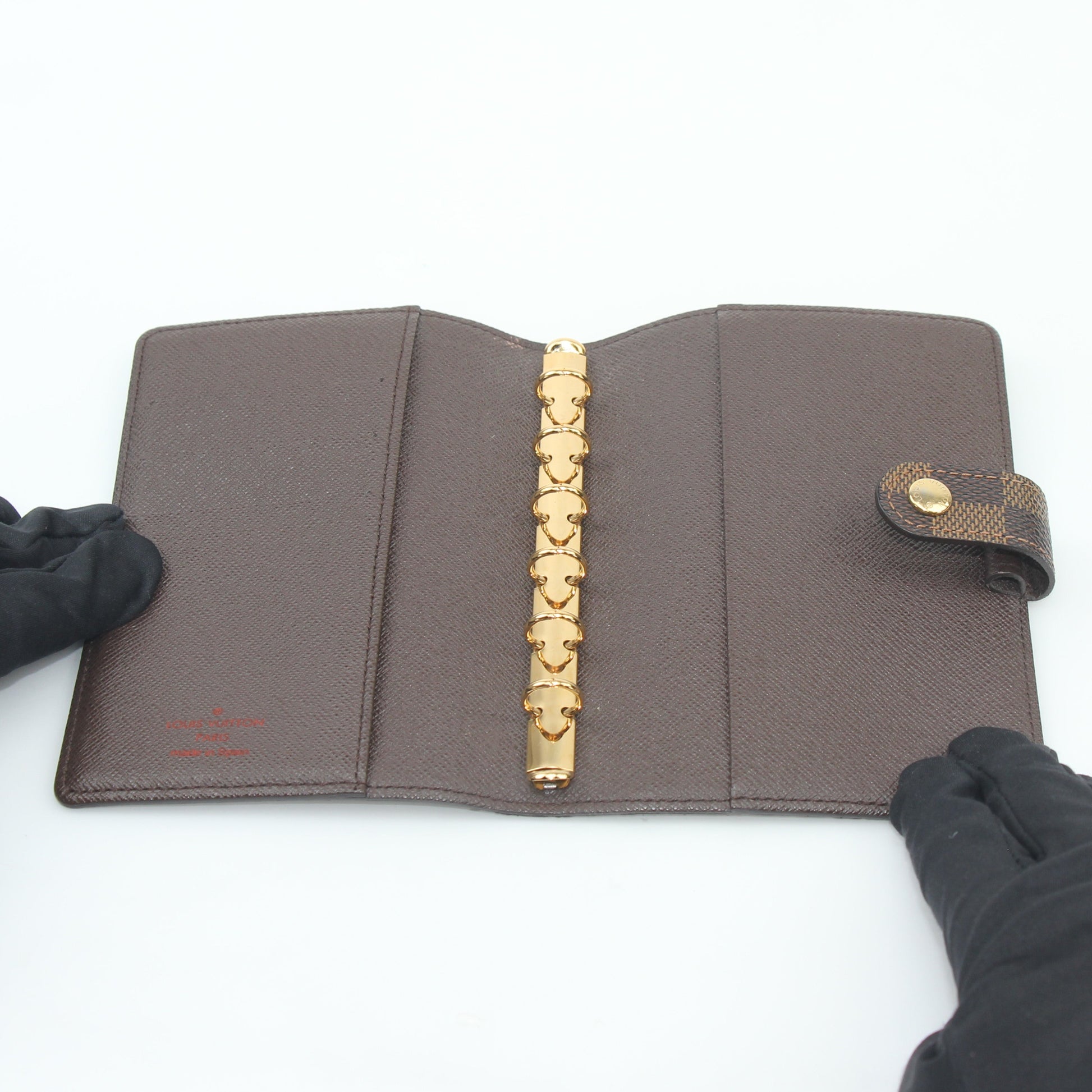 Louis Vuitton Damier Ebene Ring Agenda PM cover in brown checkered pattern with gold accents, accessory for organizing personal items.