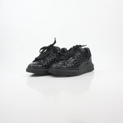 Black croc-embossed Alexander McQueen oversized sneakers with chunky soles and branding, displayed on a neutral background.