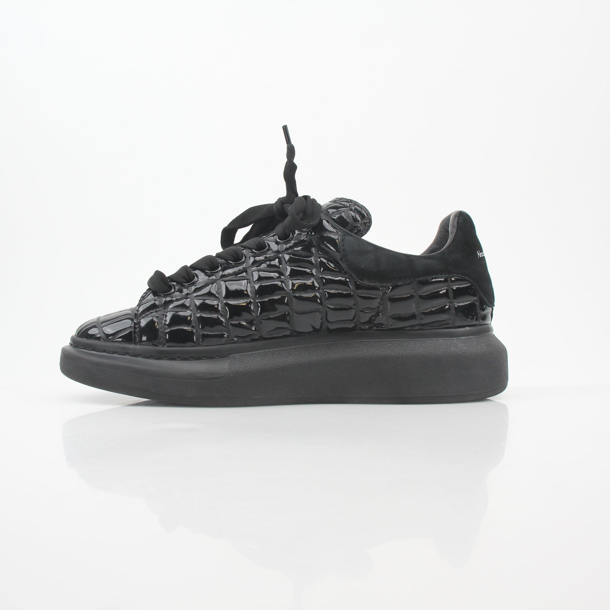 Black croc-embossed Alexander McQueen oversized sneakers with chunky soles and lace-up design, displayed on a neutral background.